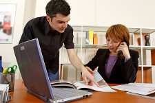 Image of two colleagues working near a laptop